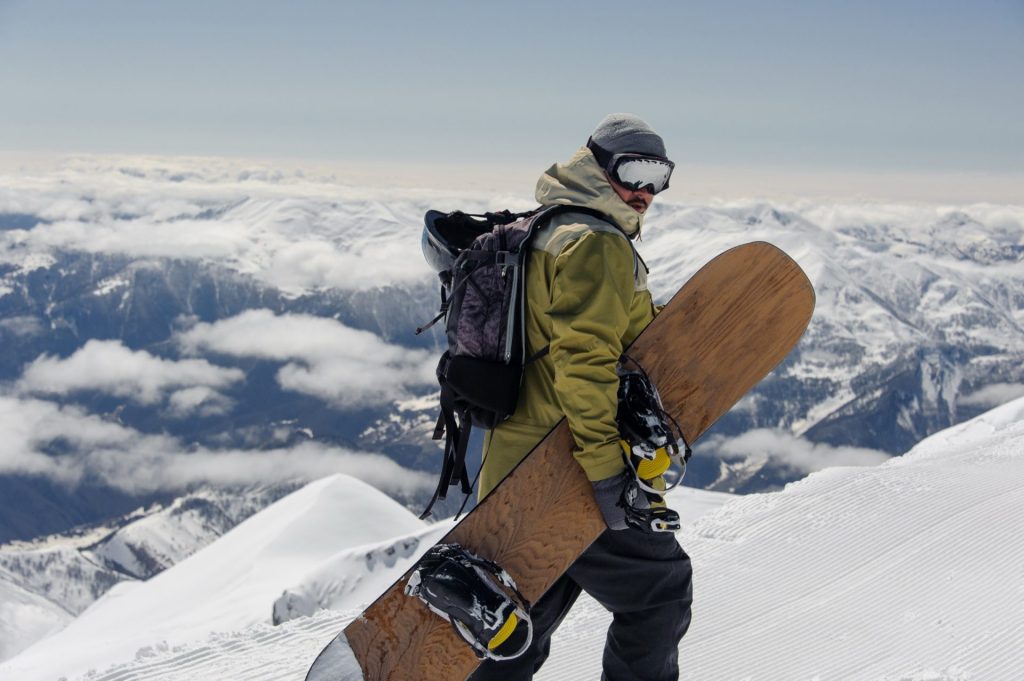 Snowboardeur portant sa planche au-dessus d'une mer de nuages