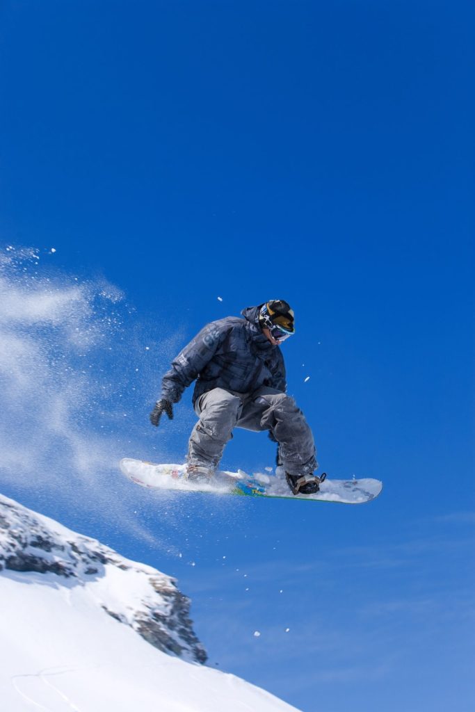 Snowboardeur en saut sur fond de ciel bleu