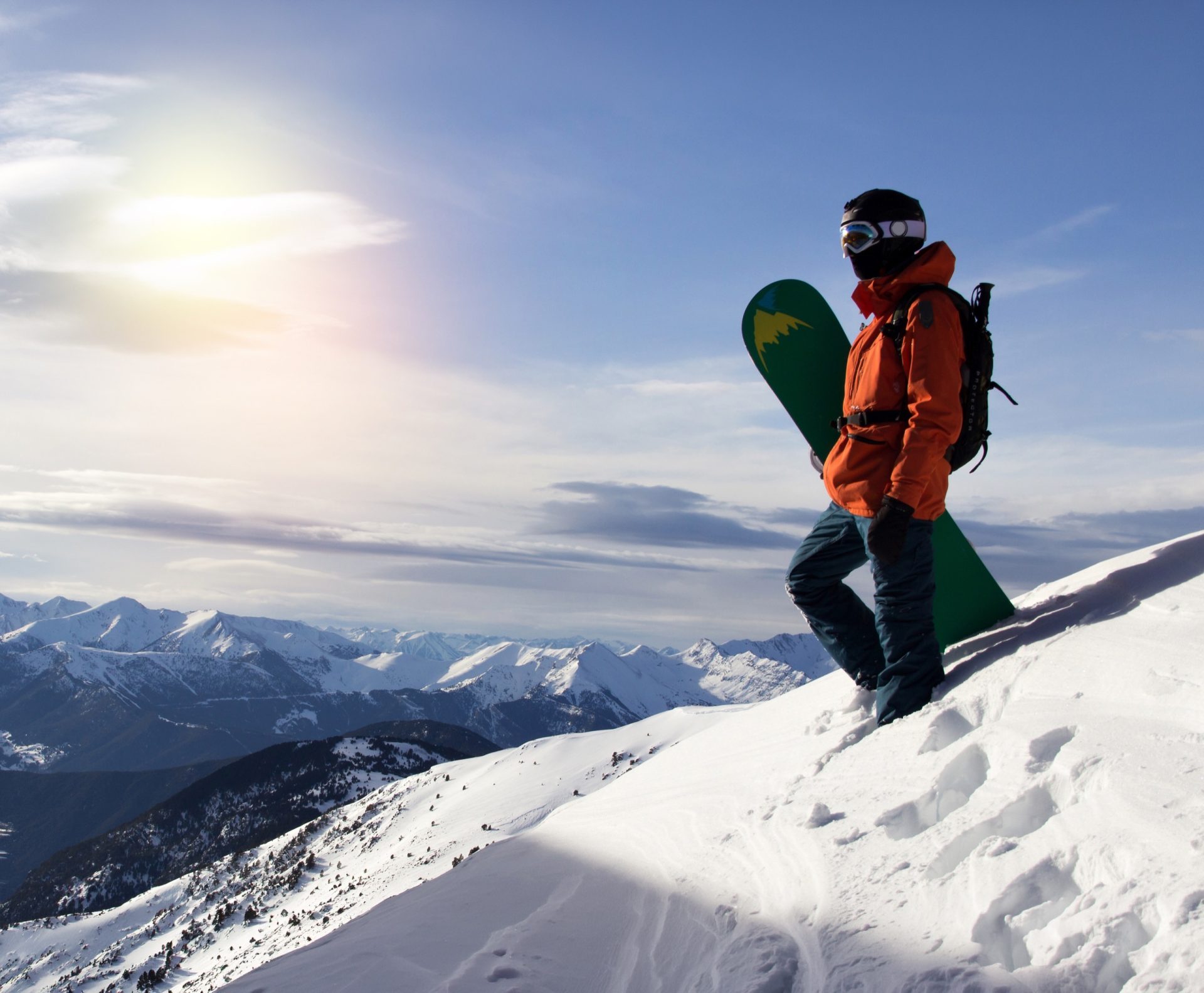 Snowboardeur avec sa planche au sommet d'une montagne enneigée